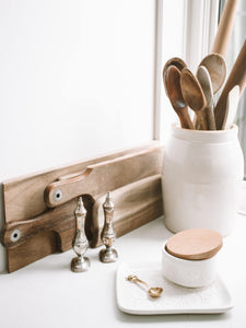 White kitchen counter with wood cutting boards and stirring spoons