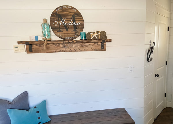 Farmhouse-style round wood sign with family name and initial