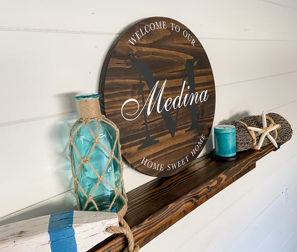 Farmhouse-style round wood sign with family name and initial